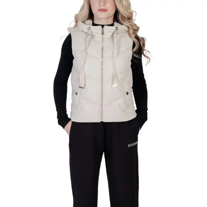 Beige hooded vest over black long-sleeved top and dark pants from Morgan De Toi