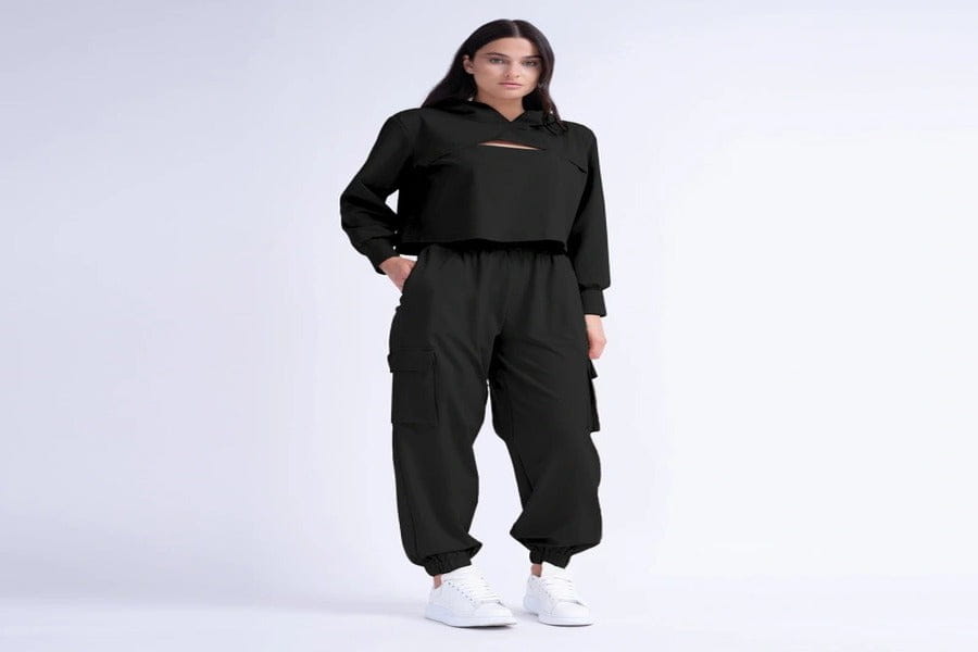 Black cargo jumpsuit with elastic cuffs paired with white sneakers in a stylish outfit.