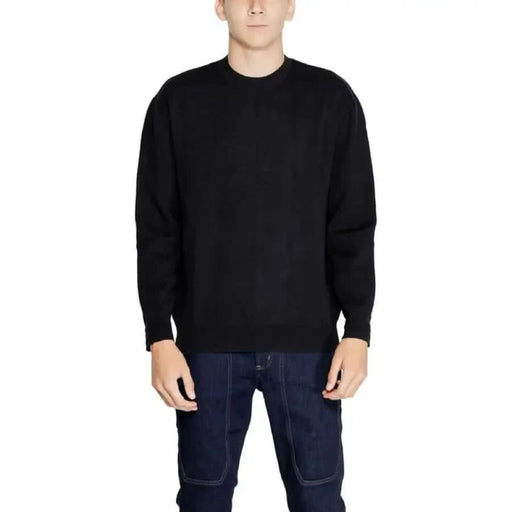 Black crewneck sweater modeled by a person from Armani Exchange Men Knitwear collection