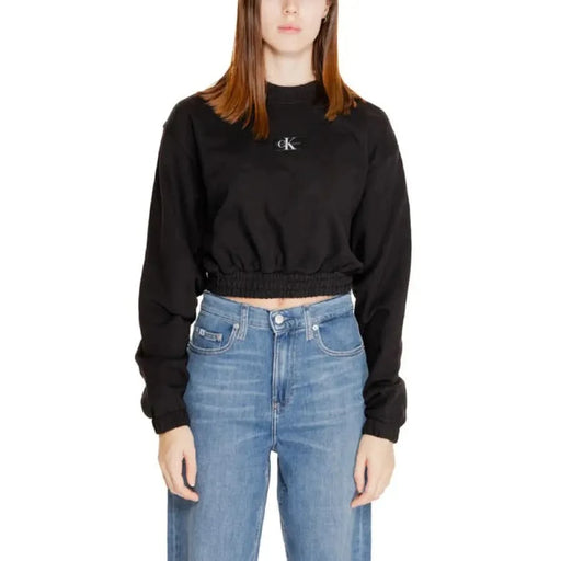 Calvin Klein women’s black cropped sweatshirt with ’CK’ logo, paired with blue jeans