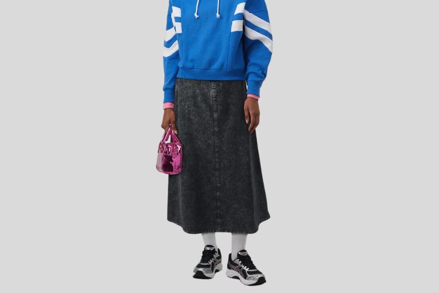 Black denim midi skirt styled with a blue hoodie and sneakers for a trendy look.