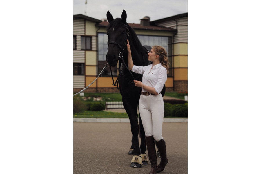 Black horse beside a person in equestrian attire embodies old money style and elegance look.