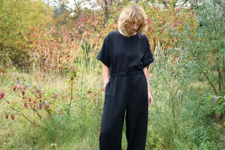 Black jumpsuit with short sleeves on a blonde individual, ideal for summer outfit ideas to shop.