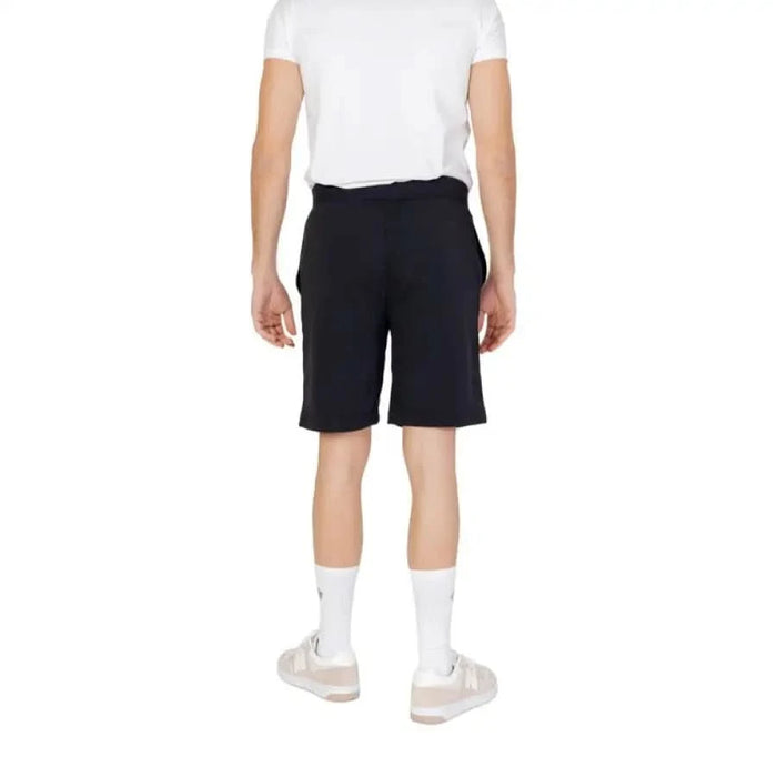 Person wearing black knee-length Calvin Klein Sport Men Shorts with white t-shirt and socks