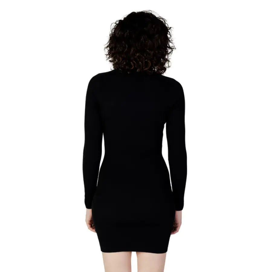 Black long-sleeved bodycon dress worn by curly dark-haired model in Calvin Klein Jeans collection