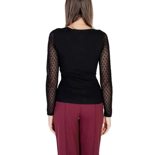 Black long-sleeved top with sheer polka dot sleeves on model from Morgan De Toi