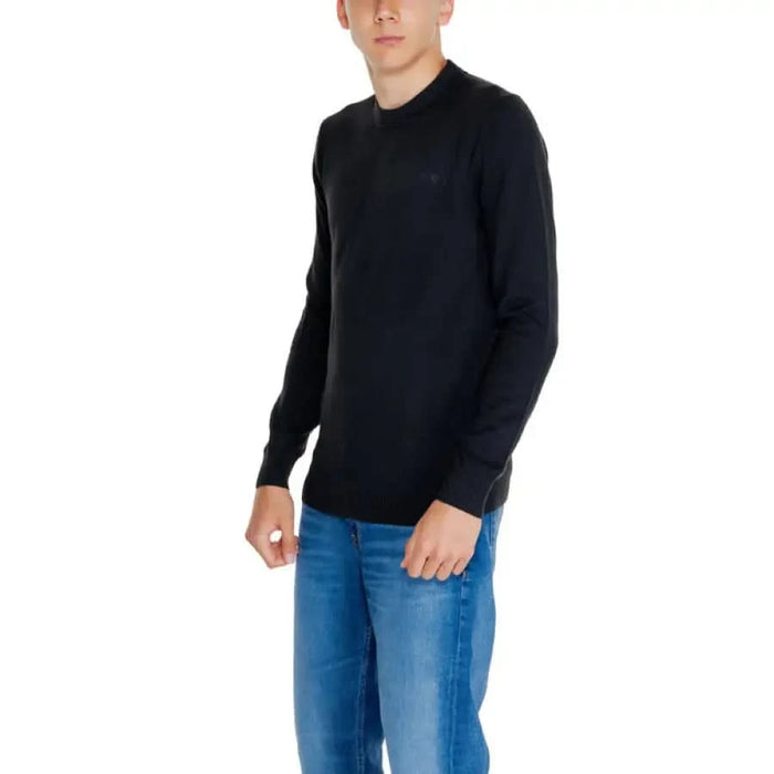 Black long-sleeved sweater with blue jeans modeled by Calvin Klein Jeans Men’s Knitwear