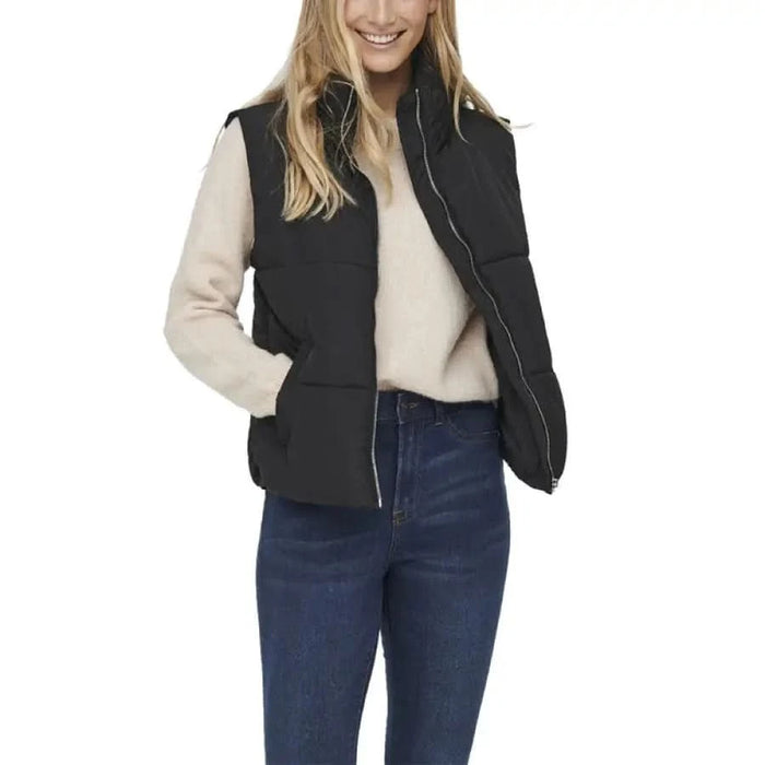 Black quilted puffer vest over cream sweater and blue jeans from Jacqueline De Yong