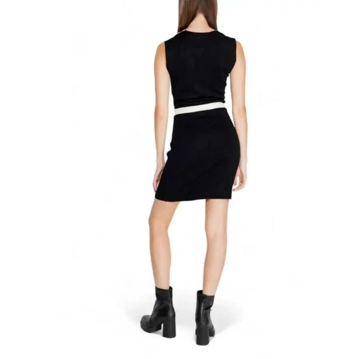 Black sleeveless mini dress with white waistband styled with black ankle boots by Morgan De Toi