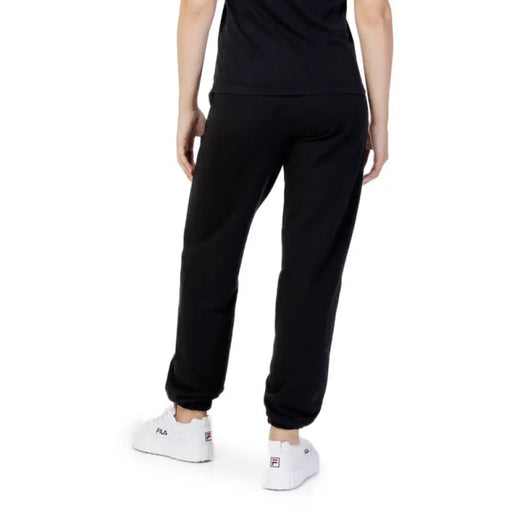 Black sweatpants worn by a person from behind, featuring Fila Women Trousers design