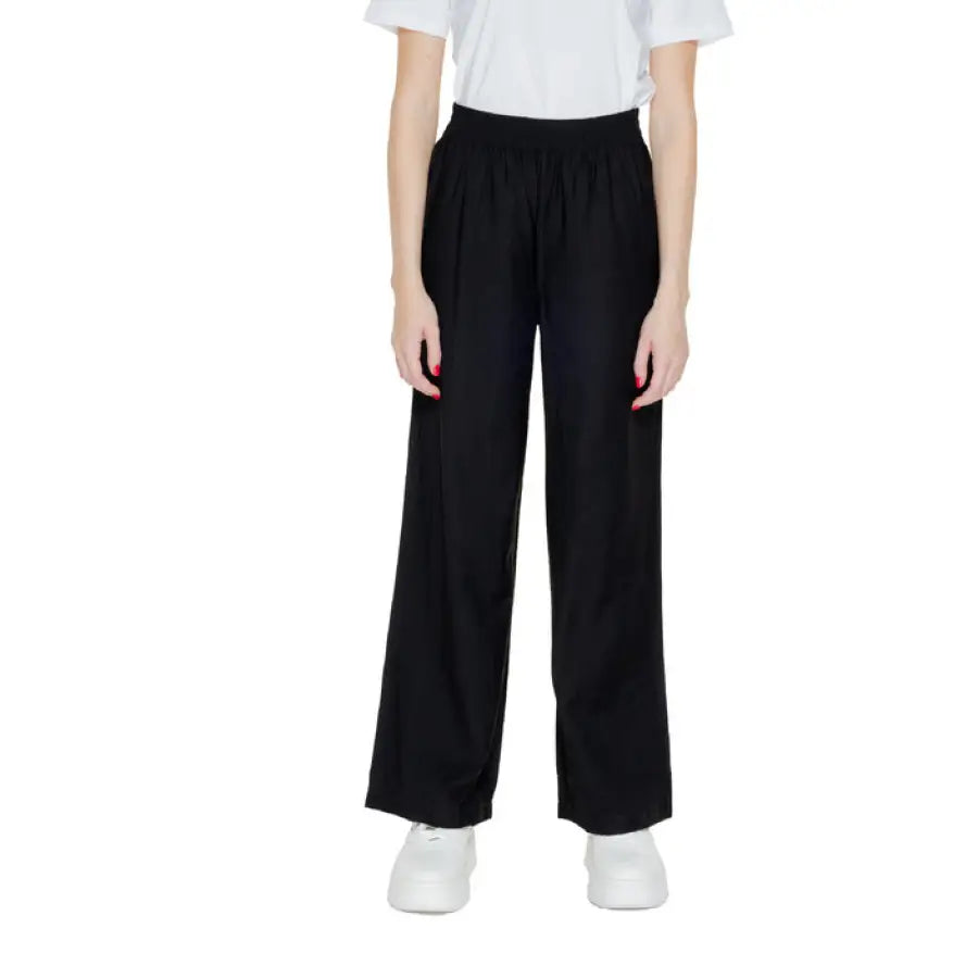 Black wide-leg trousers with a white t-shirt and white sneakers by Jacqueline De Yong