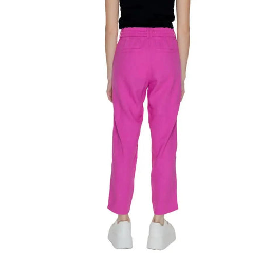 Bright pink ankle-length Only Women trousers paired with white sneakers