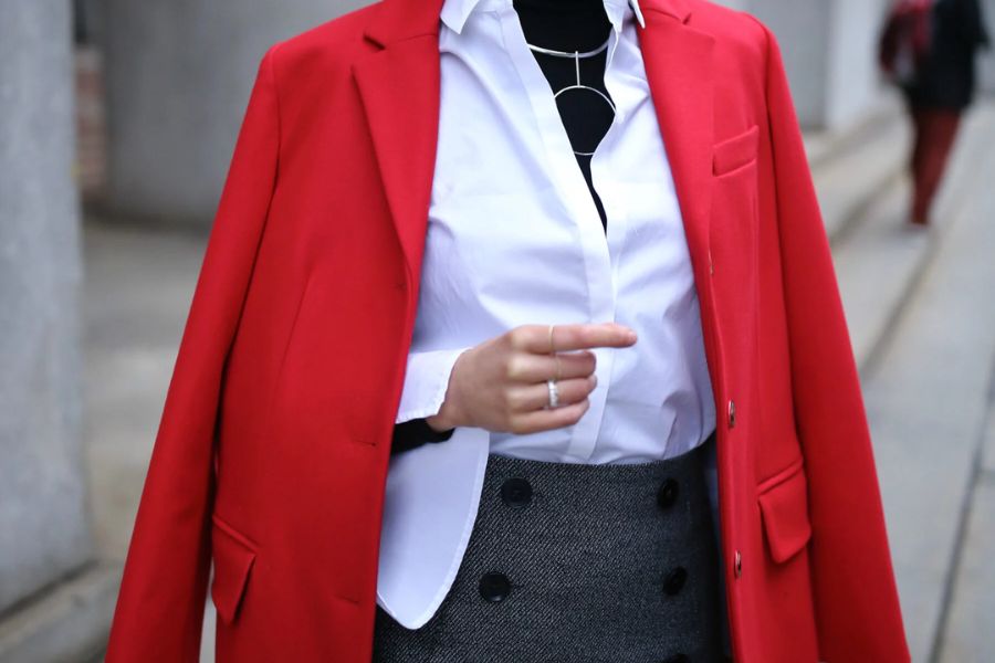 Bright red coat over a white shirt and dark vest enhancing oversized shirts style.