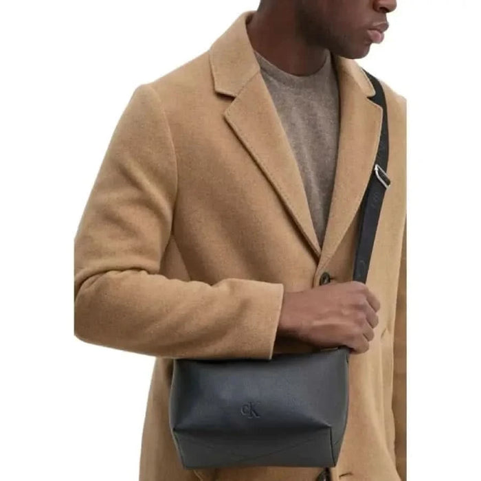 Camel wool overcoat over a light sweater with a dark leather crossbody bag