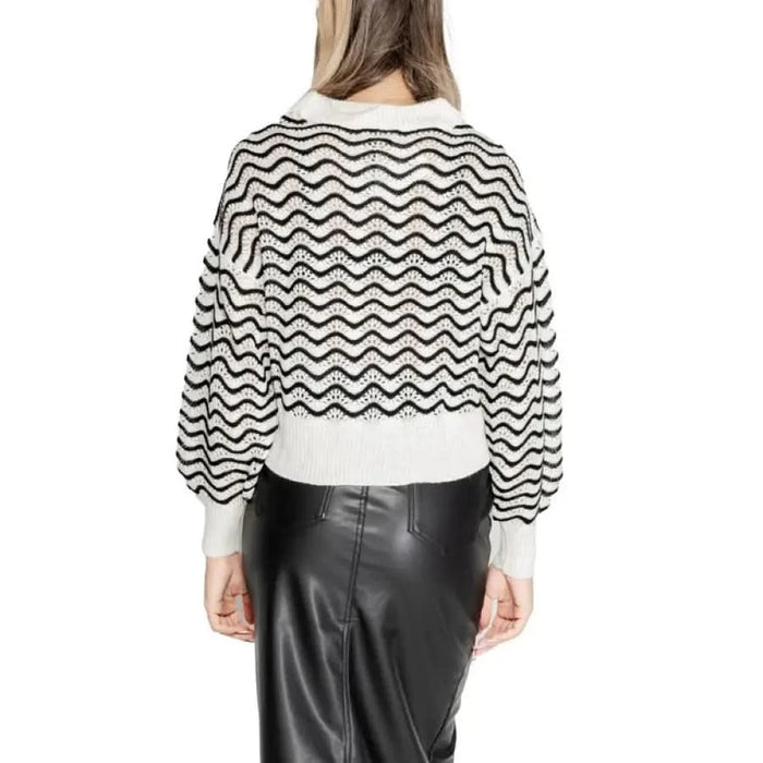 Chevron-patterned sweater with balloon sleeves over black leather skirt, viewed from behind