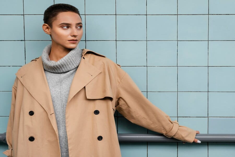 Classic beige double-breasted trench coat over gray turtleneck sweater outfit idea