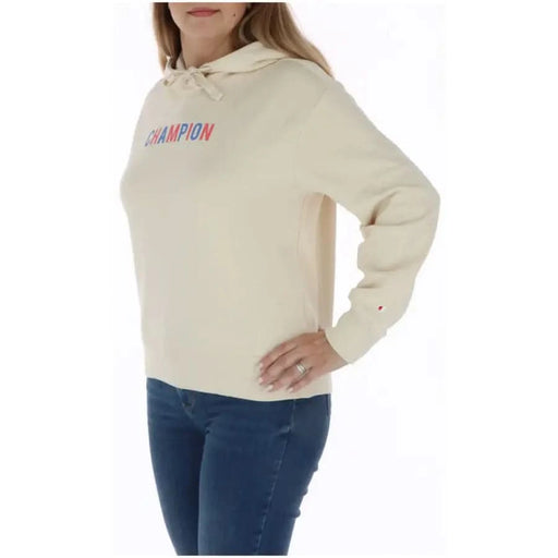 Cream-colored Champion hoodie with multicolored lettering worn by a person in blue jeans