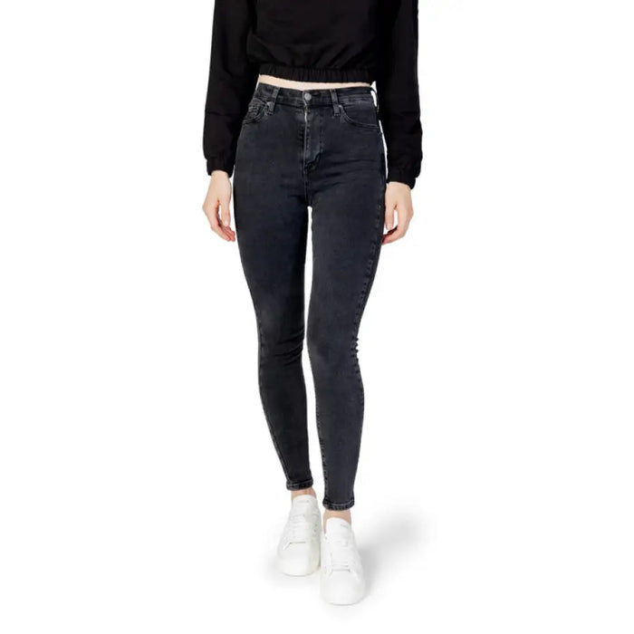 Dark-wash skinny jeans worn with a black top and white sneakers by Tommy Hilfiger