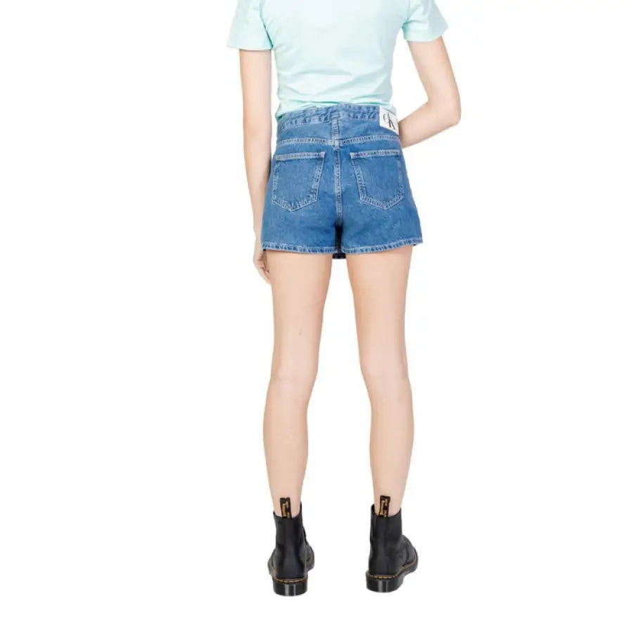 
                      
                        Calvin Klein Denim Shorts paired with a light blue shirt and black boots for women
                      
                    