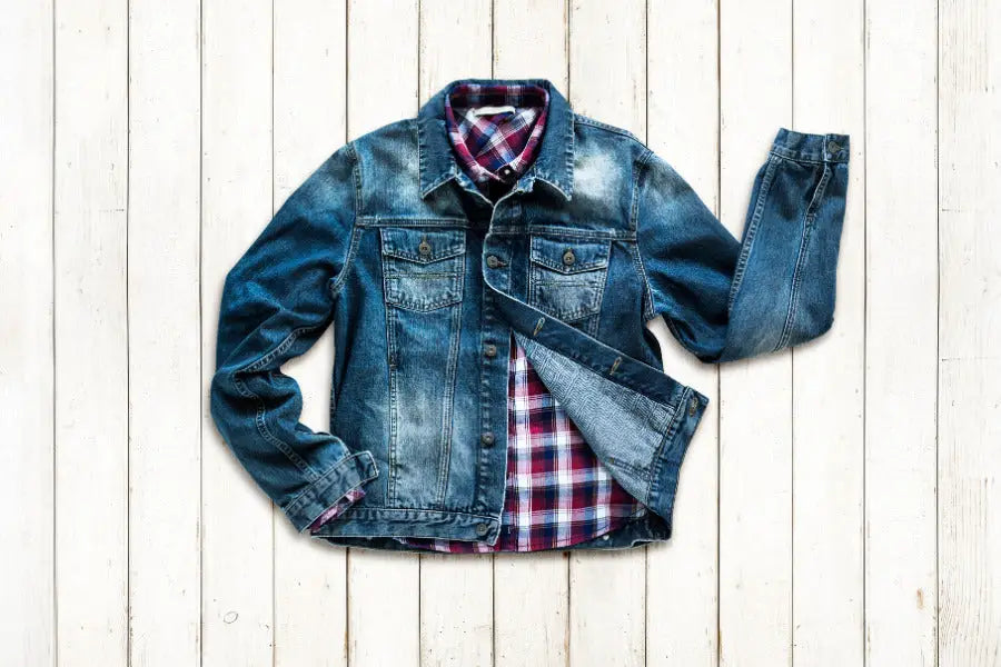 Distressed blue denim jacket layered over a red and white plaid shirt for a stylish look