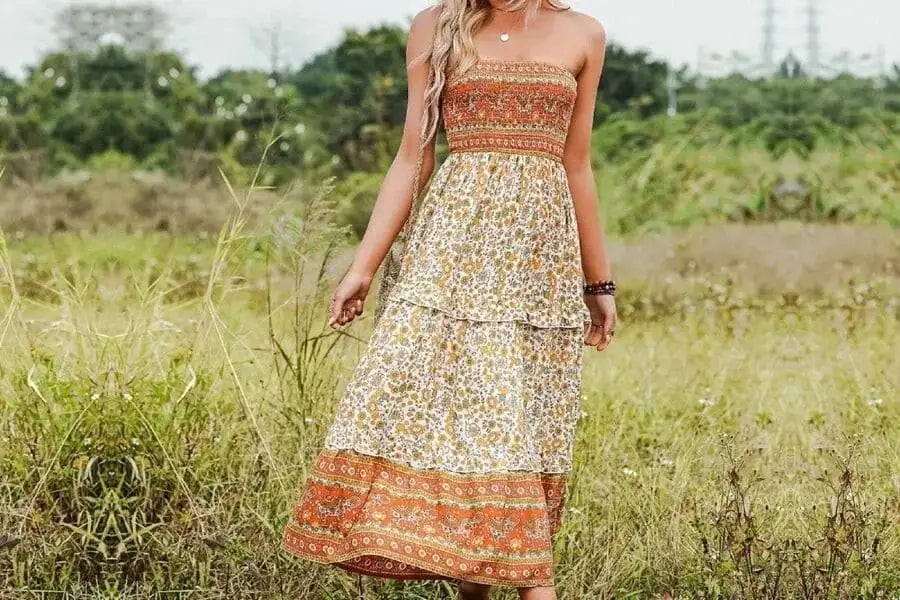 Floral gemustertes Maxikleid mit gestuftem Rock und orangefarbenen Akzenten für ein Urlaubsoutfit.