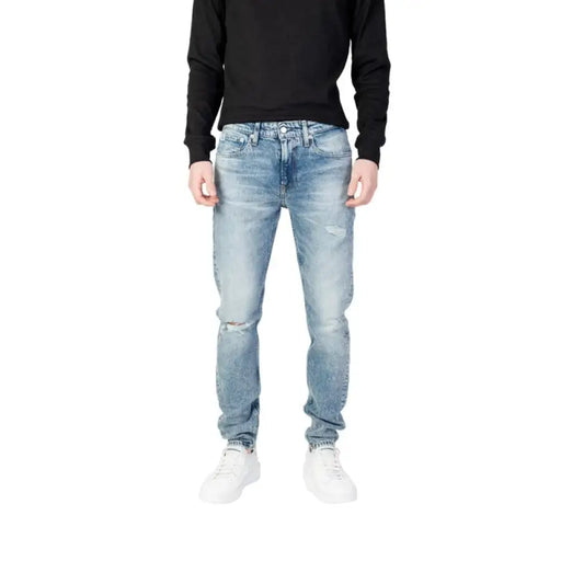 Light blue distressed Calvin Klein jeans featuring knee rips for men