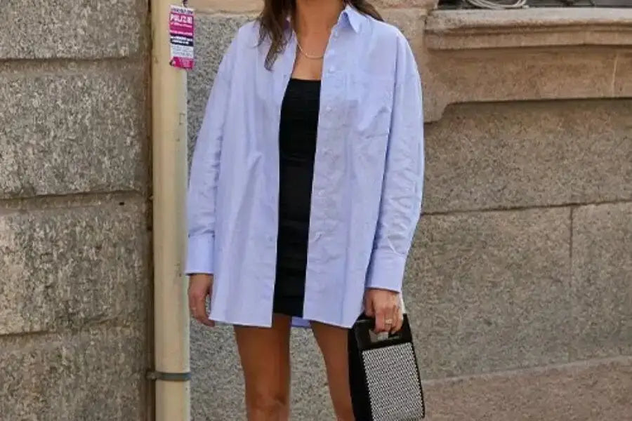 Light blue oversized shirt layered over a stylish black dress for trendy outfit ideas.