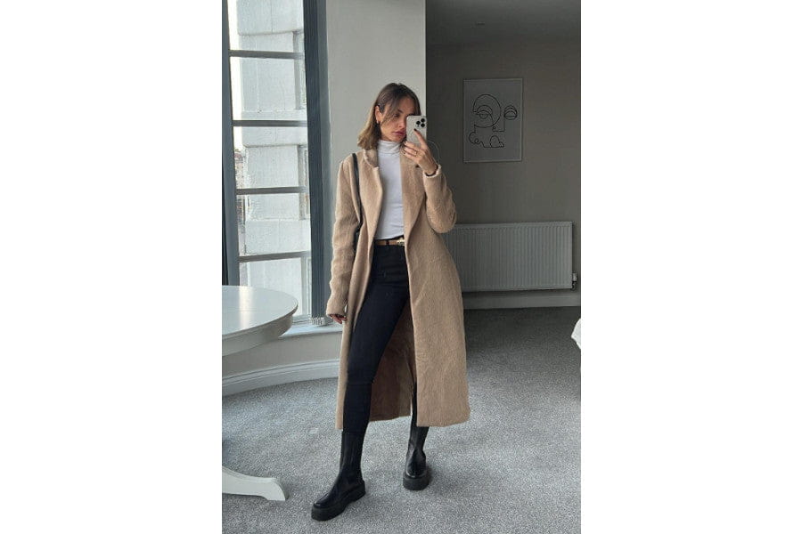 Long beige coat over white top and dark pants for minimalist apparel shopping.