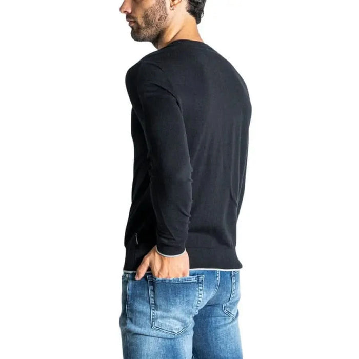 Man in black long-sleeved shirt and blue jeans showcasing Armani Exchange knitwear