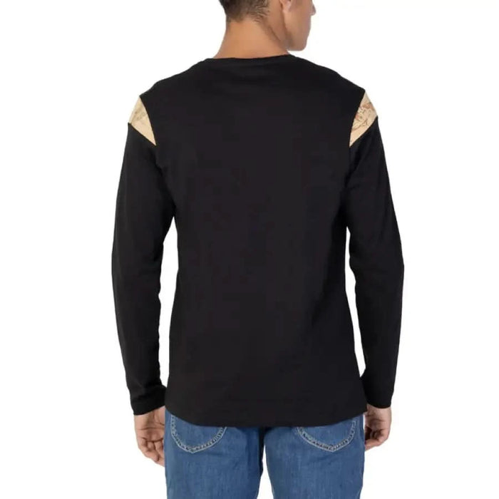 Man wearing Alviero Martini Prima Classe black shirt with gold patch on back