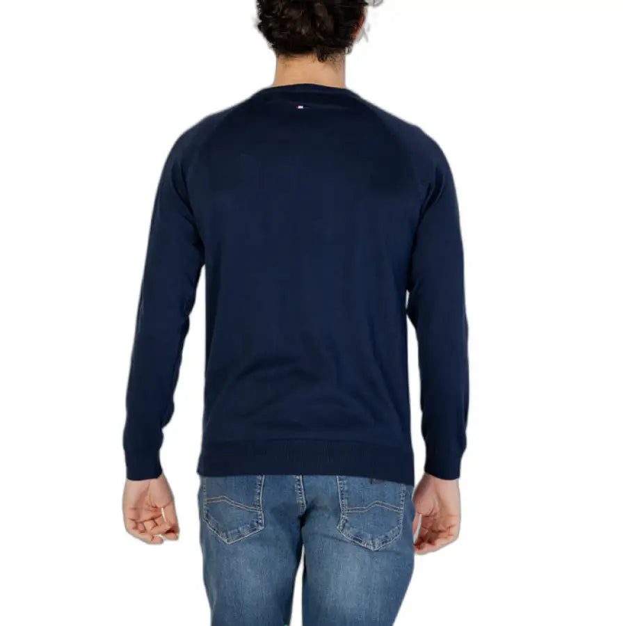 A man in a blue U.S. Polo Assn. sweater and jeans, showcasing men’s knitwear from U.S. Polo Assn