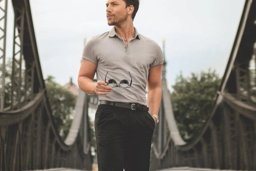 Man in a gray polo shirt on a bridge, exemplifying smart casual men summer style.