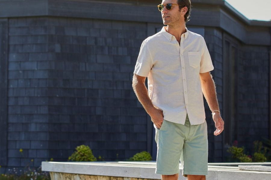 Man in a white short-sleeved shirt and light-colored shorts for smart casual men summer style.