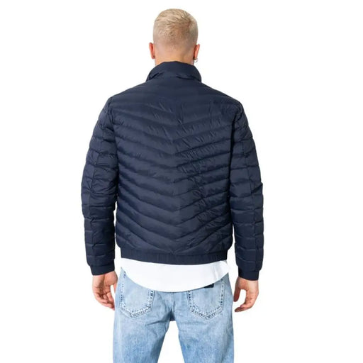 Navy blue quilted puffer jacket worn by a man with short blond hair from Armani Exchange