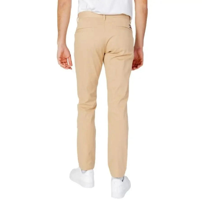 Pair of beige chino pants worn with white sneakers from Tommy Hilfiger Jeans Men Trousers