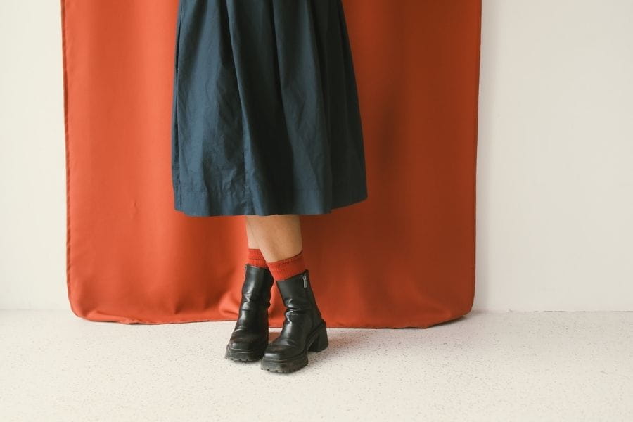 Black ankle boots with chunky heels paired with a dark skirt in a retro outfit.