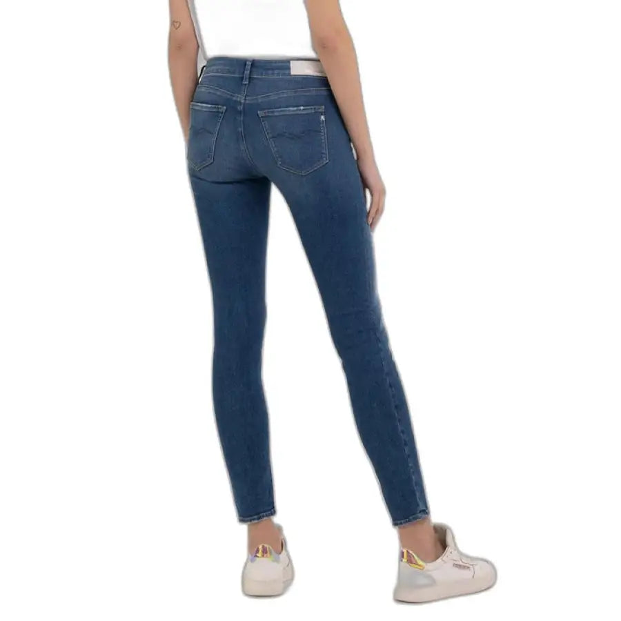 Pair of blue skinny jeans by Replay worn with white sneakers