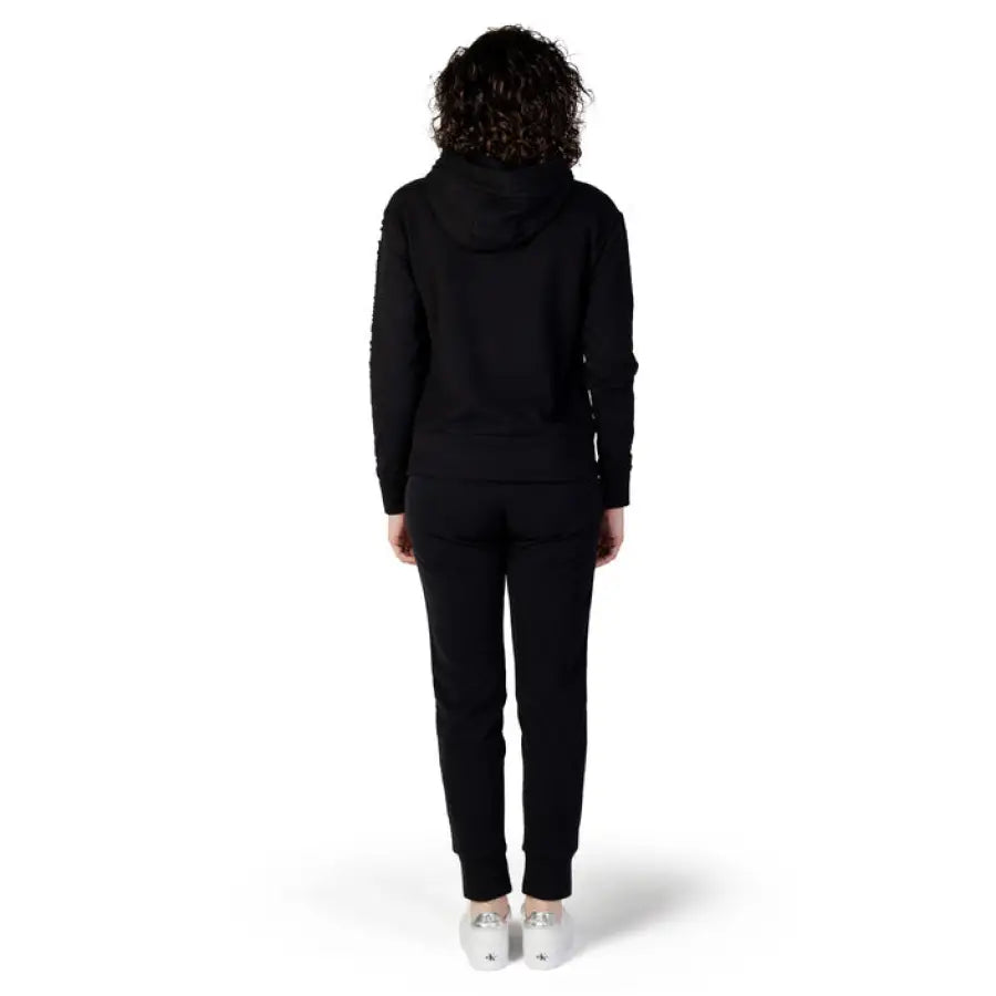 Person in all-black Ea7 Women Jumpsuit standing with their back to the camera