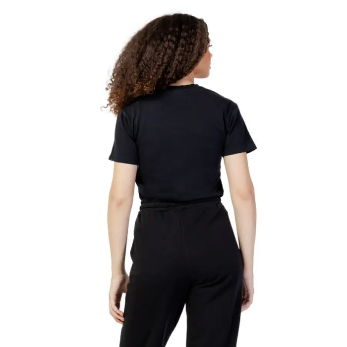 Person with curly dark hair wearing a black Fila Women T-Shirt, viewed from behind