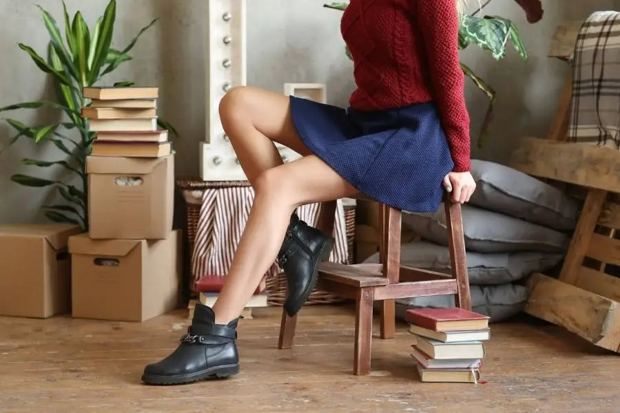 Person in a red sweater and blue skirt seated on a wooden stool for first date fashion.