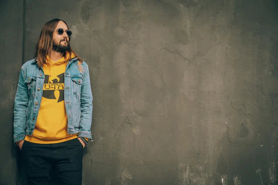 Person in denim jacket over yellow hoodie and sunglasses for stylish attire.