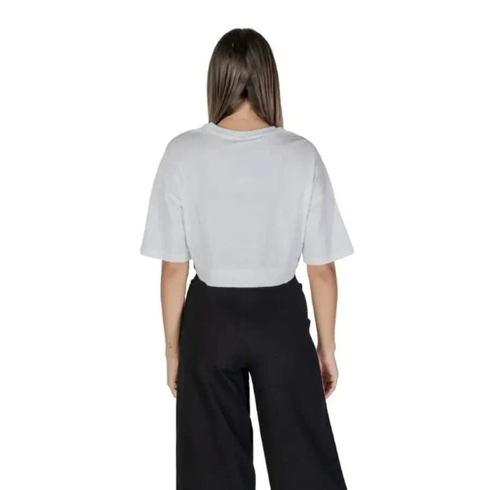 Person in white Moschino Underwear t-shirt and black wide-leg pants viewed from behind