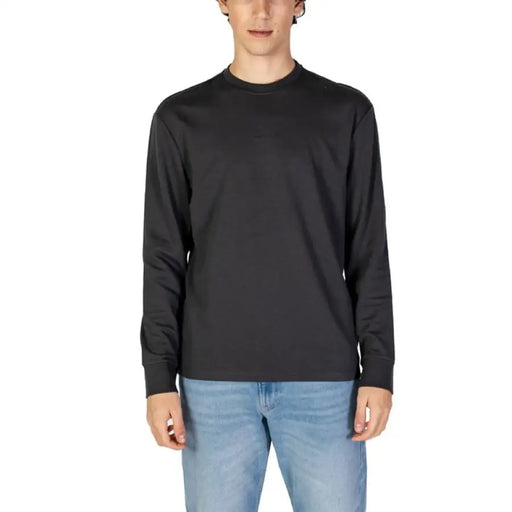 Plain black long-sleeve crewneck sweatshirt paired with light blue jeans from Gas