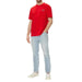 Red Tommy Hilfiger T-shirt paired with light blue jeans and white sneakers