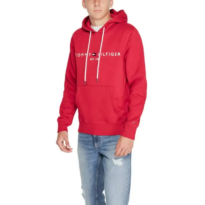 Red Tommy Hilfiger hoodie with white logo text and drawstrings displayed in Men Sweatshirts