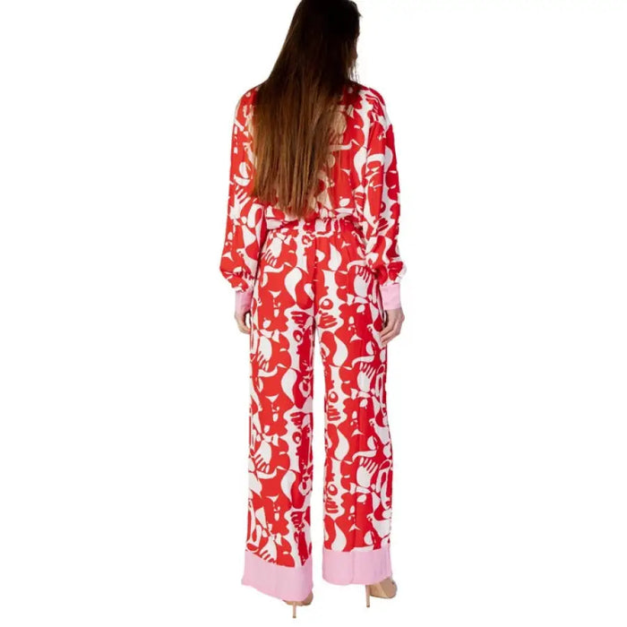 Red and white patterned pajama set with long sleeves and pants worn by a woman with brown hair