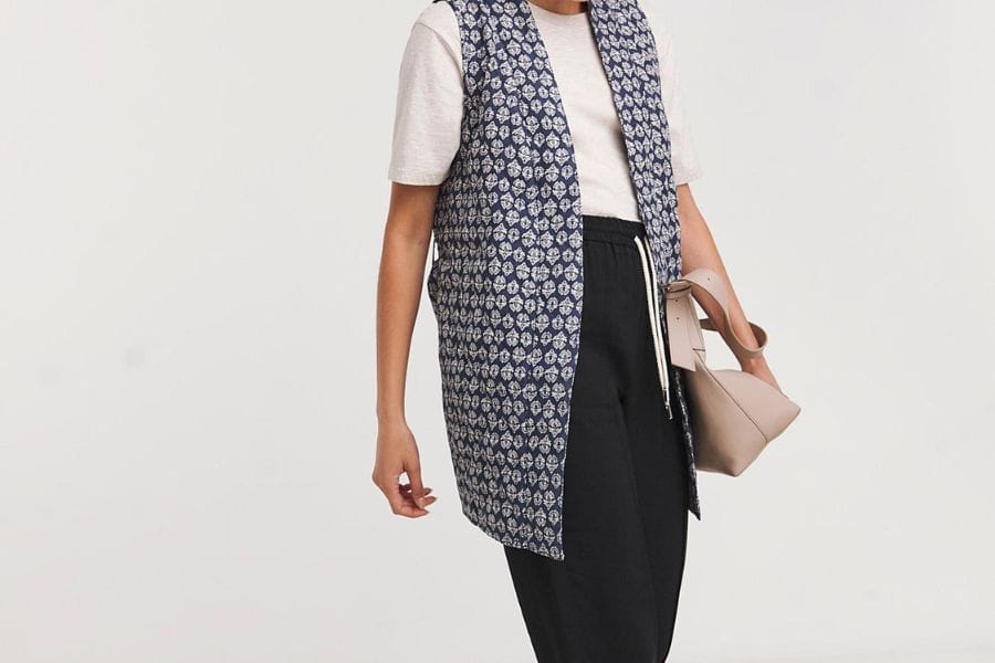 Sleeveless patterned vest layered over a white shirt and dark pants for summer work outfits