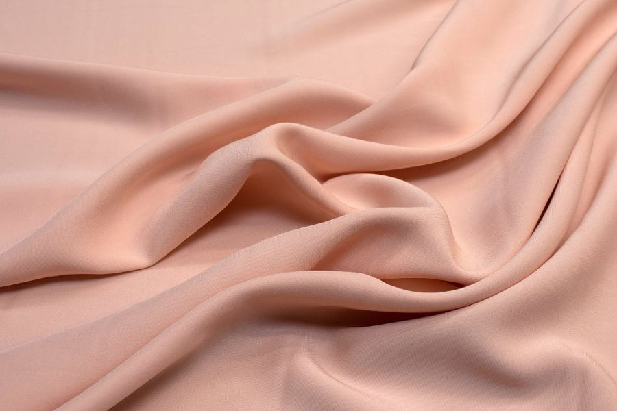 Soft, flowing pale pink fabric showcasing gentle folds suitable for summer weather.