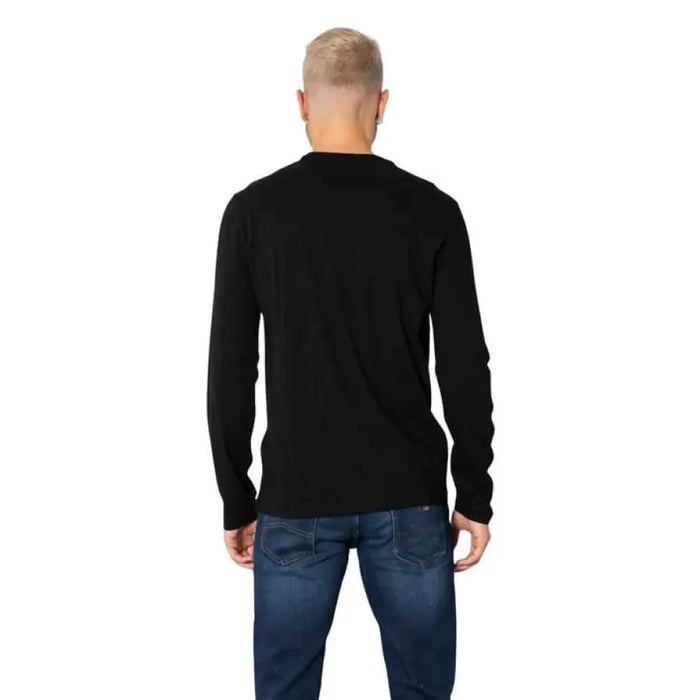 Back view of person in Armani Exchange black long-sleeved shirt and blue jeans