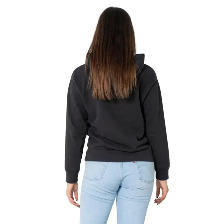 Back view of person wearing Levi’s black sweatshirt and light blue jeans with long brown hair